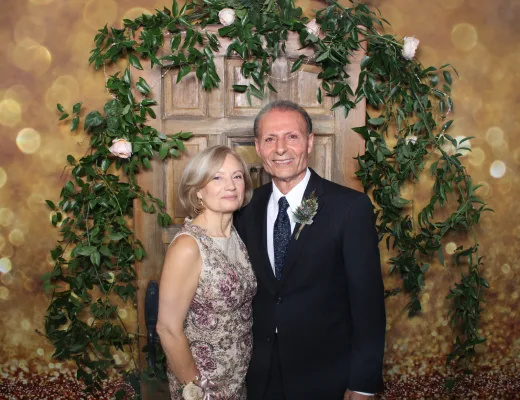 Couple photographed in a greenery arch and rustic door set with a gold bokeh backdrop