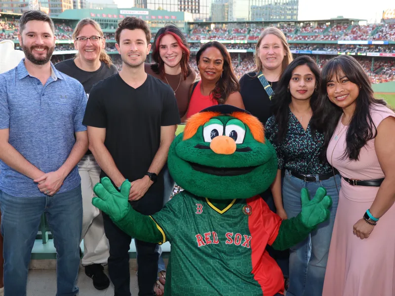 A corporate group posing together at a staged photo op with a costumed mascot