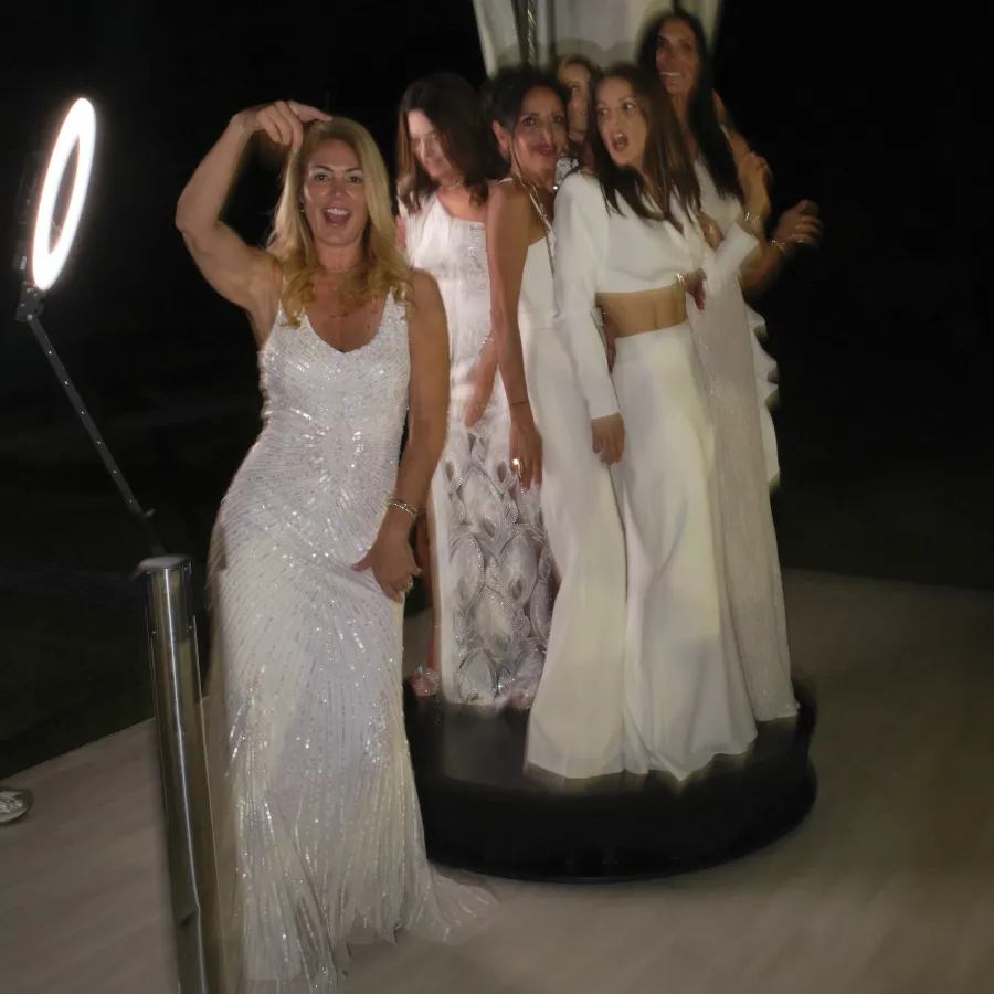 Five guests in formal wear posing together on the 360 video booth platform