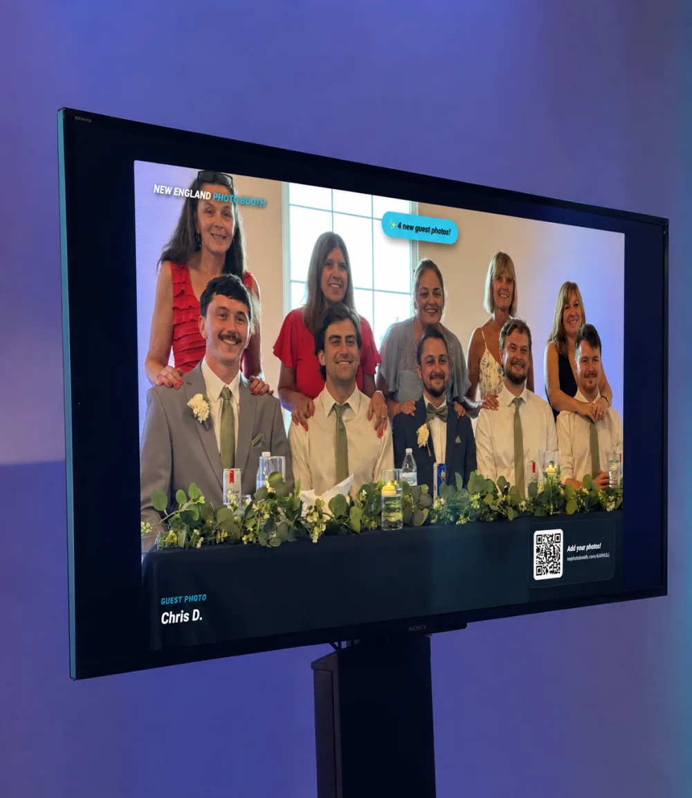 The GuestView live slideshow running on a TV at a real event, with the scan-to-add QR right on screen