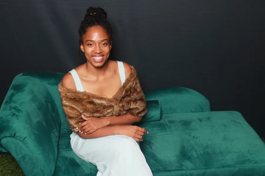 Guest in a formal gown photographed on a green velvet couch against a black backdrop