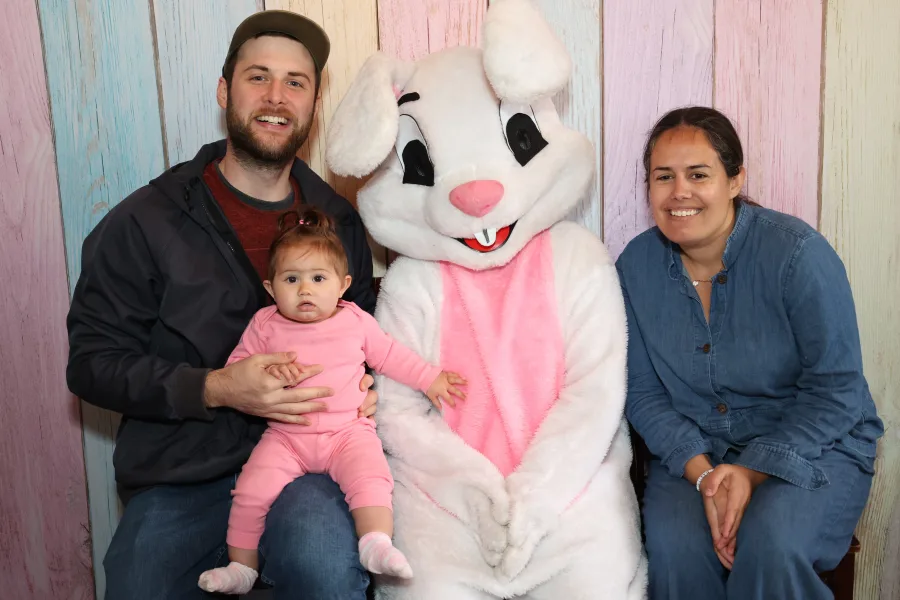 Family with a baby posing with the Easter Bunny at a spring character photo op