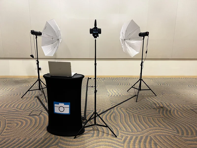 Photo op setup: Canon camera on a tripod between two umbrella strobes with a laptop on a draped table